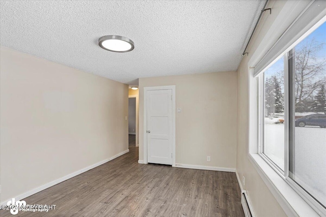 3936 W 88th Ave, Anchorage, AK 99502 - unfurnished room with baseboards, baseboard heating, wood finished floors, and a textured ceiling