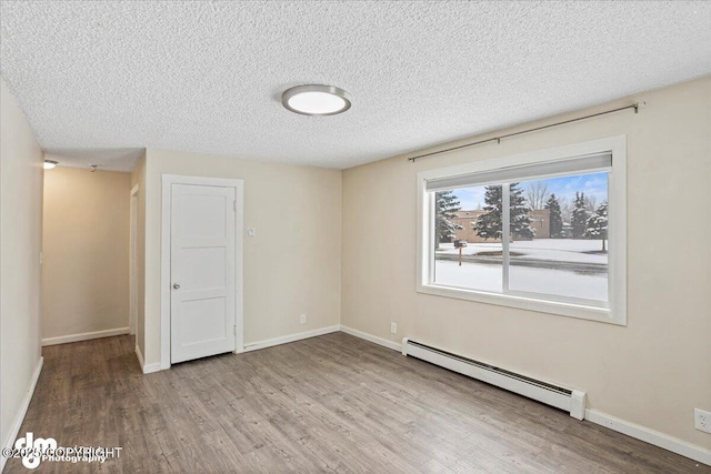 3936 W 88th Ave, Anchorage, AK 99502 - spare room with baseboard heating, a textured ceiling, wood finished floors, and baseboards