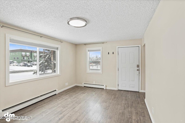 3936 W 88th Ave, Anchorage, AK 99502 - unfurnished room featuring baseboards, a baseboard heating unit, a textured ceiling, and wood finished floors