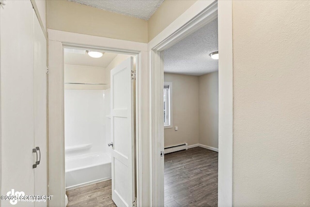 3936 W 88th Ave, Anchorage, AK 99502 - corridor featuring a baseboard heating unit, a textured ceiling, and wood finished floors