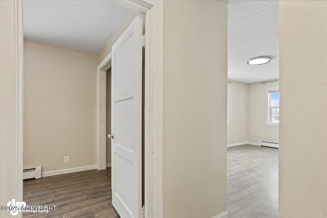 3936 W 88th Ave, Anchorage, AK 99502 - hall with baseboards, a baseboard heating unit, wood finished floors, and a textured ceiling