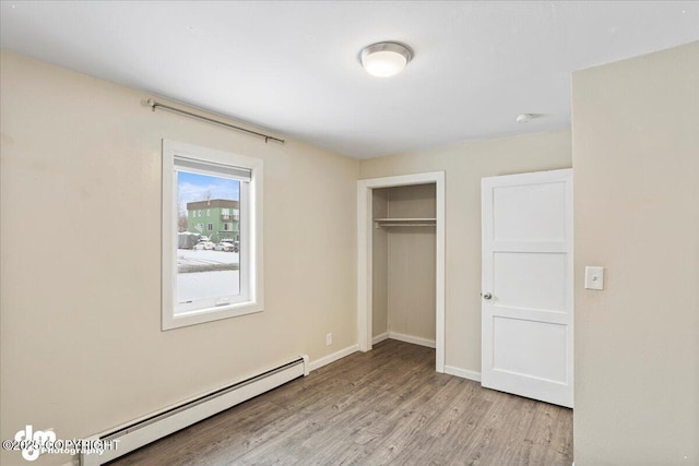 3936 W 88th Ave, Anchorage, AK 99502 - unfurnished bedroom with light wood finished floors, a closet, a baseboard heating unit, and baseboards