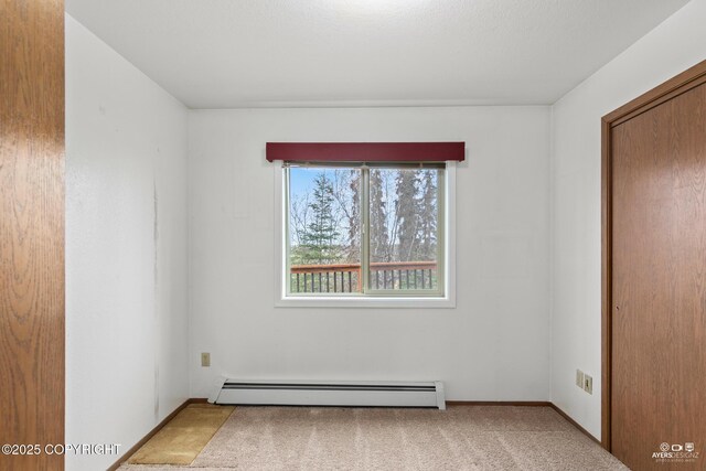 carpeted spare room with a baseboard heating unit and baseboards