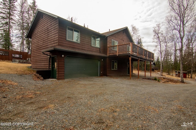 exterior space with dirt driveway, an attached garage, and a deck