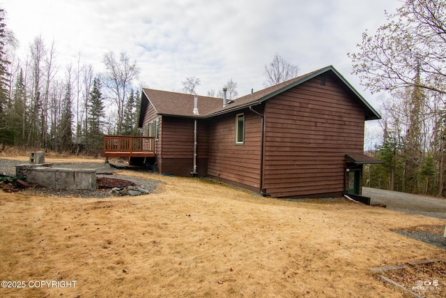 view of property exterior with roof with shingles and a wooden deck