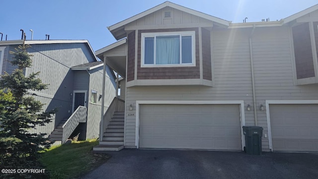6244 Ophir Dr, Anchorage, AK 99504 - view of front facade with an attached garage, stairway, asphalt driveway, and board and batten siding