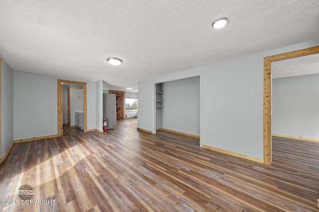 8153 Stewart Mountain Dr, Eagle River, AK 99577 - unfurnished bedroom with a textured ceiling, wood finished floors, baseboards, freestanding refrigerator, and a closet