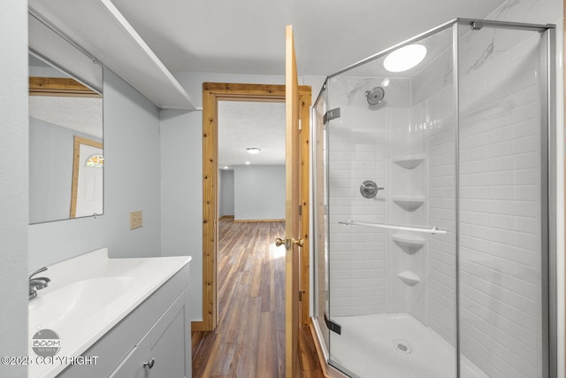 8153 Stewart Mountain Dr, Eagle River, AK 99577 - full bathroom featuring vanity, a shower stall, wood finished floors, baseboards, and a textured ceiling