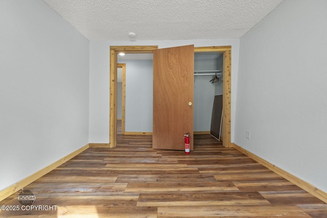 8153 Stewart Mountain Dr, Eagle River, AK 99577 - unfurnished bedroom with wood finished floors, baseboards, and a textured ceiling