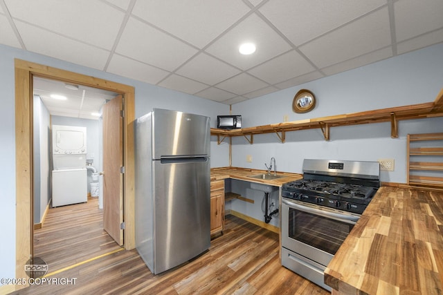 8153 Stewart Mountain Dr, Eagle River, AK 99577 - kitchen featuring appliances with stainless steel finishes, wooden counters, stacked washer and clothes dryer, a paneled ceiling, and wood finished floors