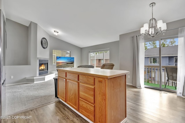 2460 Lochenshire Pl Unit 21, Anchorage, AK 99504 - kitchen with open floor plan, light wood-type flooring, a chandelier, vaulted ceiling, and a tile fireplace