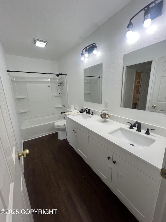 bathroom with wood finished floors, toilet, double vanity, and a sink