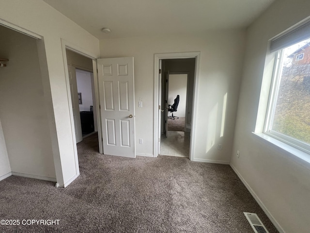 unfurnished bedroom featuring visible vents, multiple windows, carpet, and baseboards
