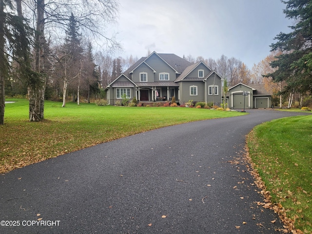 craftsman inspired home with a front lawn, an outdoor structure, covered porch, and a detached garage