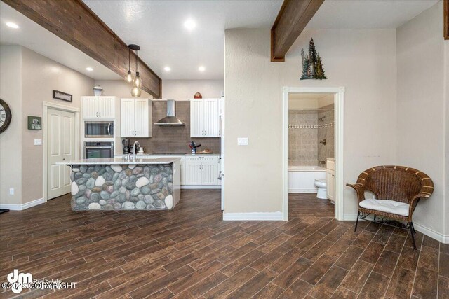 13598 N Willow Dr, Willow, AK 99688 - kitchen featuring wall chimney exhaust hood, white cabinetry, light countertops, stainless steel appliances, and beam ceiling