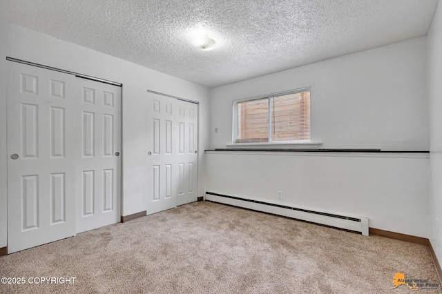 525 E 14th Ave, Anchorage, AK 99501 - unfurnished bedroom featuring baseboard heating, carpet flooring, two closets, and a textured ceiling