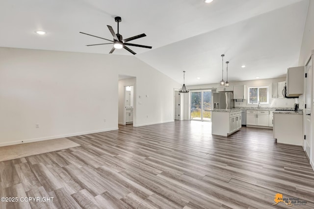unfurnished living room with a ceiling fan, lofted ceiling, wood finished floors, recessed lighting, and baseboards