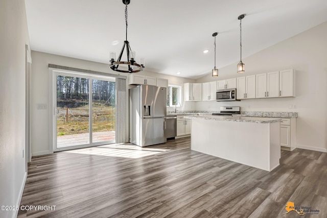 kitchen featuring appliances with stainless steel finishes, a chandelier, plenty of natural light, a sink, and lofted ceiling