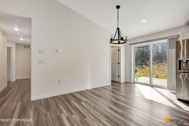 unfurnished dining area featuring a chandelier, wood finished floors, and baseboards