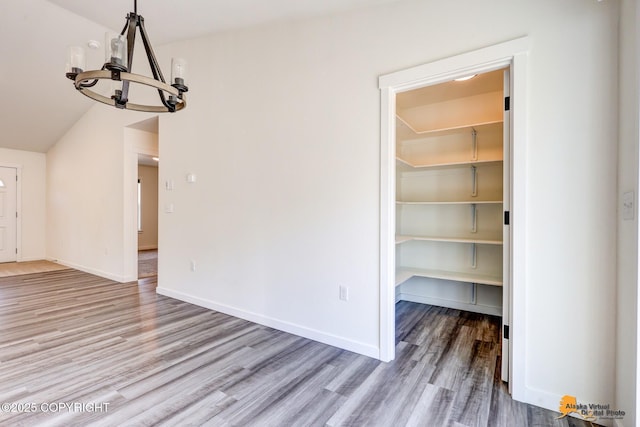 unfurnished dining area featuring a chandelier, wood finished floors, and baseboards