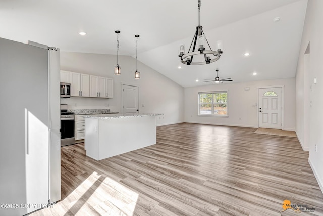 kitchen with stainless steel appliances, vaulted ceiling, a chandelier, light wood-style floors, and white cabinets