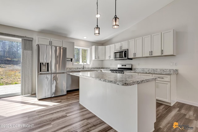 kitchen featuring appliances with stainless steel finishes, light countertops, dark wood-style floors, a kitchen island, and decorative light fixtures