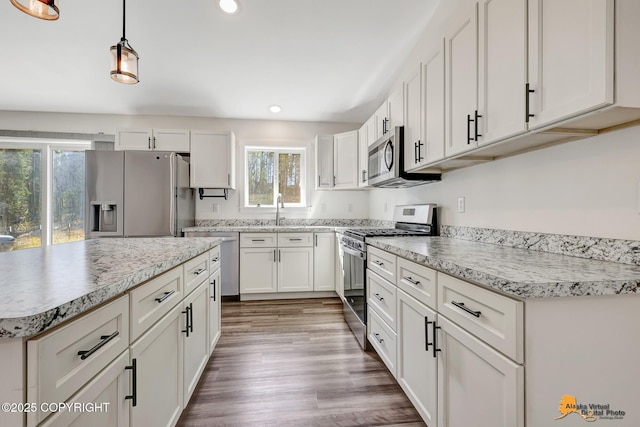 kitchen featuring appliances with stainless steel finishes, recessed lighting, a sink, white cabinetry, and wood finished floors