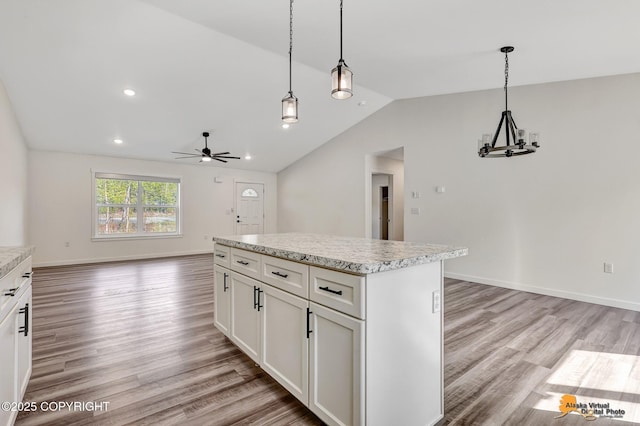 kitchen with lofted ceiling, light wood-style flooring, a ceiling fan, a kitchen island, and hanging light fixtures