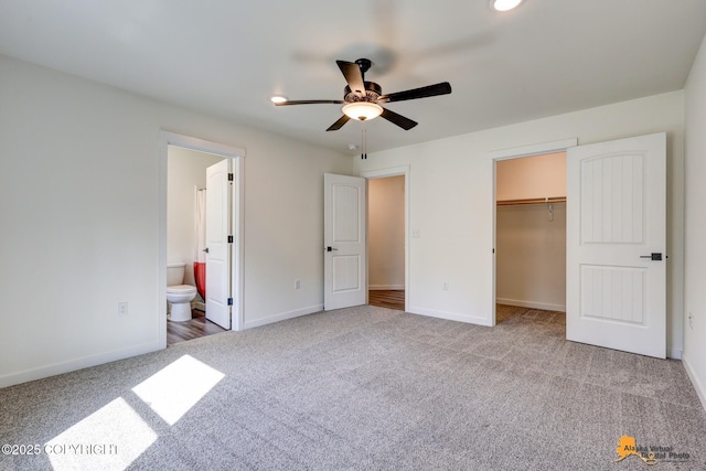unfurnished bedroom with carpet flooring, baseboards, a spacious closet, and a closet