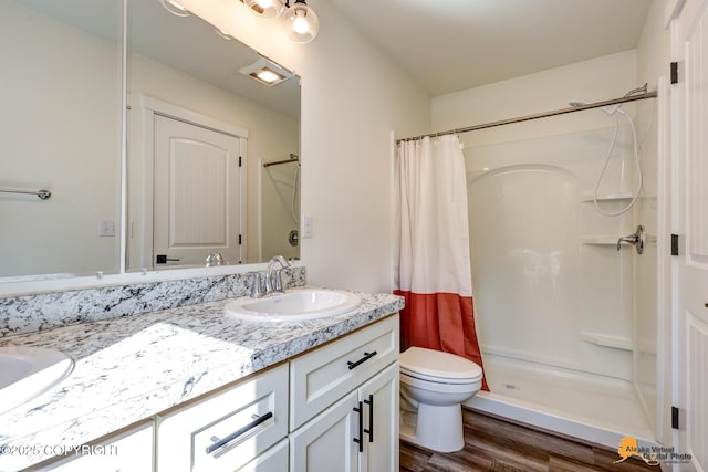 bathroom with a stall shower, wood finished floors, vanity, and toilet