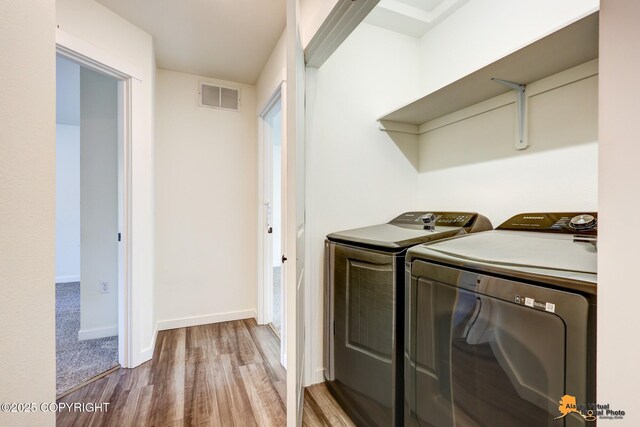 laundry area featuring washer and dryer, wood finished floors, and baseboards