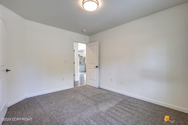 carpeted spare room featuring baseboards