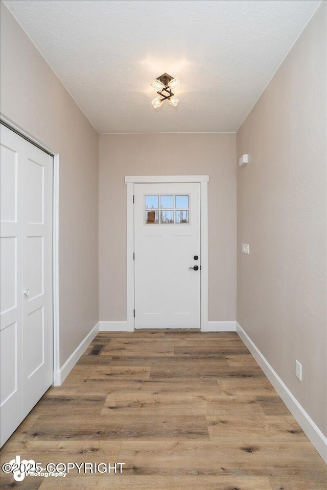 doorway to outside with light wood finished floors and baseboards