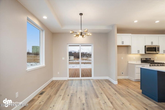 kitchen featuring appliances with stainless steel finishes, an inviting chandelier, white cabinetry, and light wood-style floors