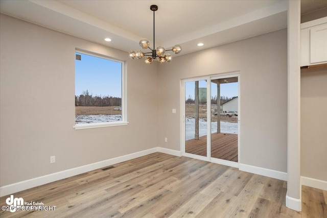 unfurnished dining area featuring an inviting chandelier, recessed lighting, light wood-style flooring, and baseboards