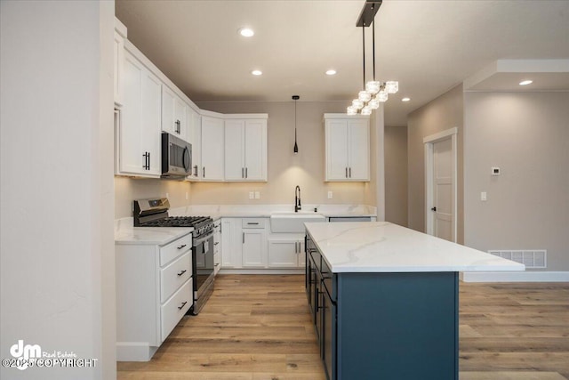 kitchen with light wood-style floors, appliances with stainless steel finishes, white cabinets, a sink, and visible vents