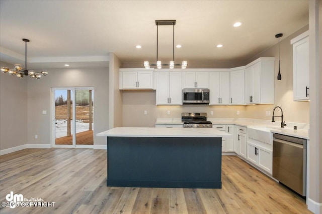 kitchen featuring white cabinetry, a sink, appliances with stainless steel finishes, light countertops, and a center island