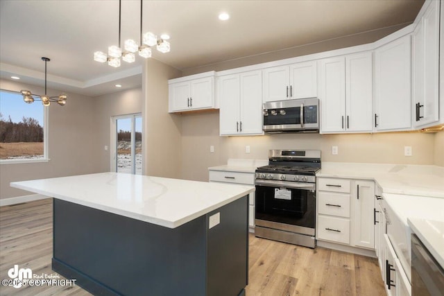 kitchen with white cabinets, appliances with stainless steel finishes, a chandelier, and light wood-type flooring