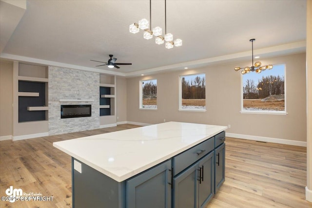 kitchen with a center island, hanging light fixtures, light wood-style flooring, and ceiling fan with notable chandelier
