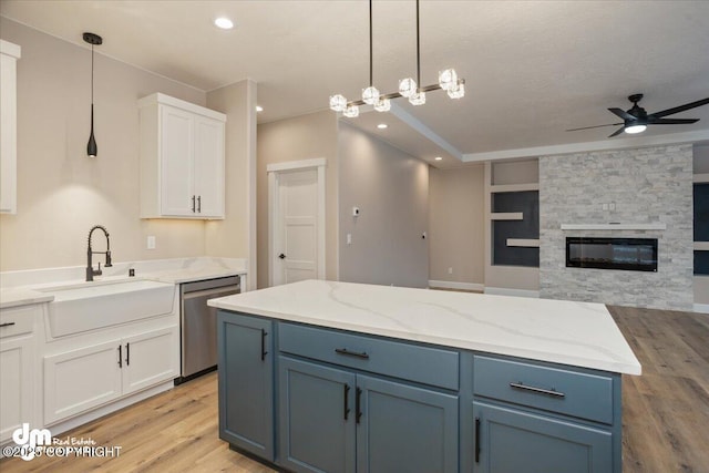 kitchen with light wood finished floors, a sink, a ceiling fan, dishwasher, and white cabinets