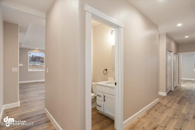 hall with baseboards, recessed lighting, and light wood finished floors