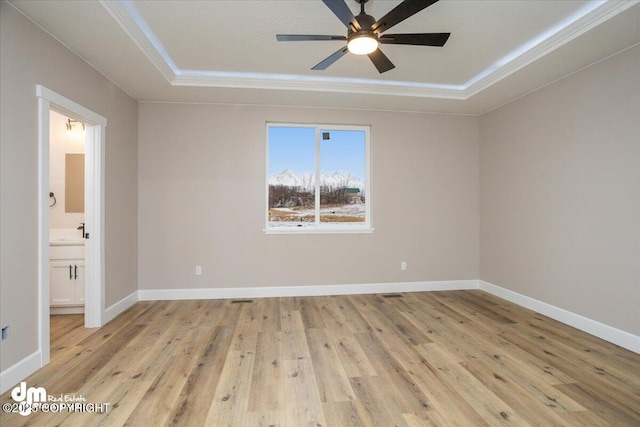 unfurnished room with a raised ceiling, a ceiling fan, light wood-style floors, and ornamental molding