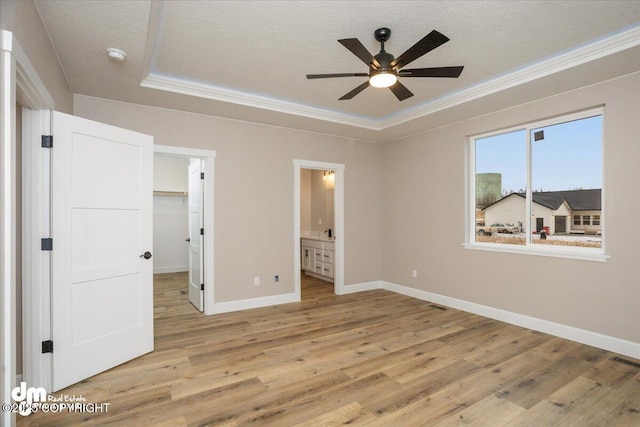 unfurnished bedroom featuring ornamental molding, a textured ceiling, baseboards, and light wood-type flooring