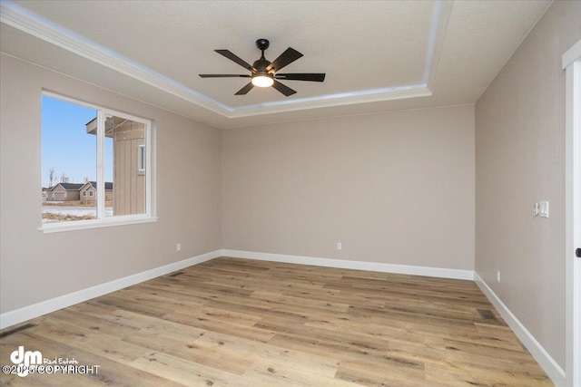 empty room featuring ceiling fan, crown molding, visible vents, baseboards, and wood finished floors