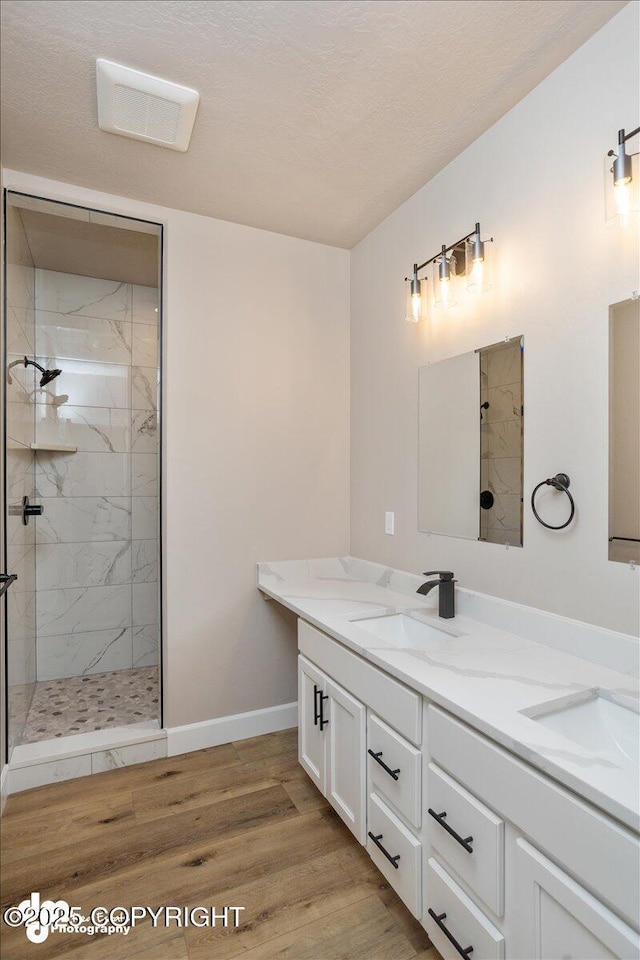 full bath featuring baseboards, visible vents, a marble finish shower, and a sink