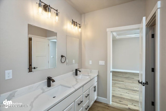 bathroom with double vanity, a sink, wood finished floors, and baseboards