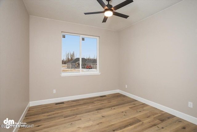unfurnished room featuring baseboards, visible vents, wood finished floors, and ceiling fan