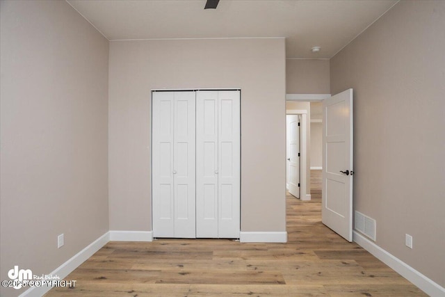 unfurnished bedroom featuring a closet, visible vents, baseboards, and light wood-style floors