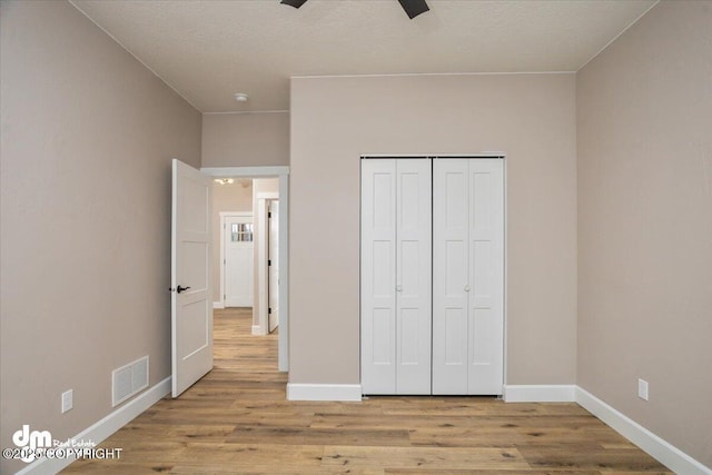 unfurnished bedroom featuring baseboards, visible vents, and wood finished floors