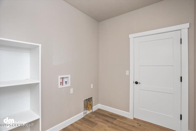 washroom featuring baseboards, hookup for a washing machine, wood finished floors, and laundry area